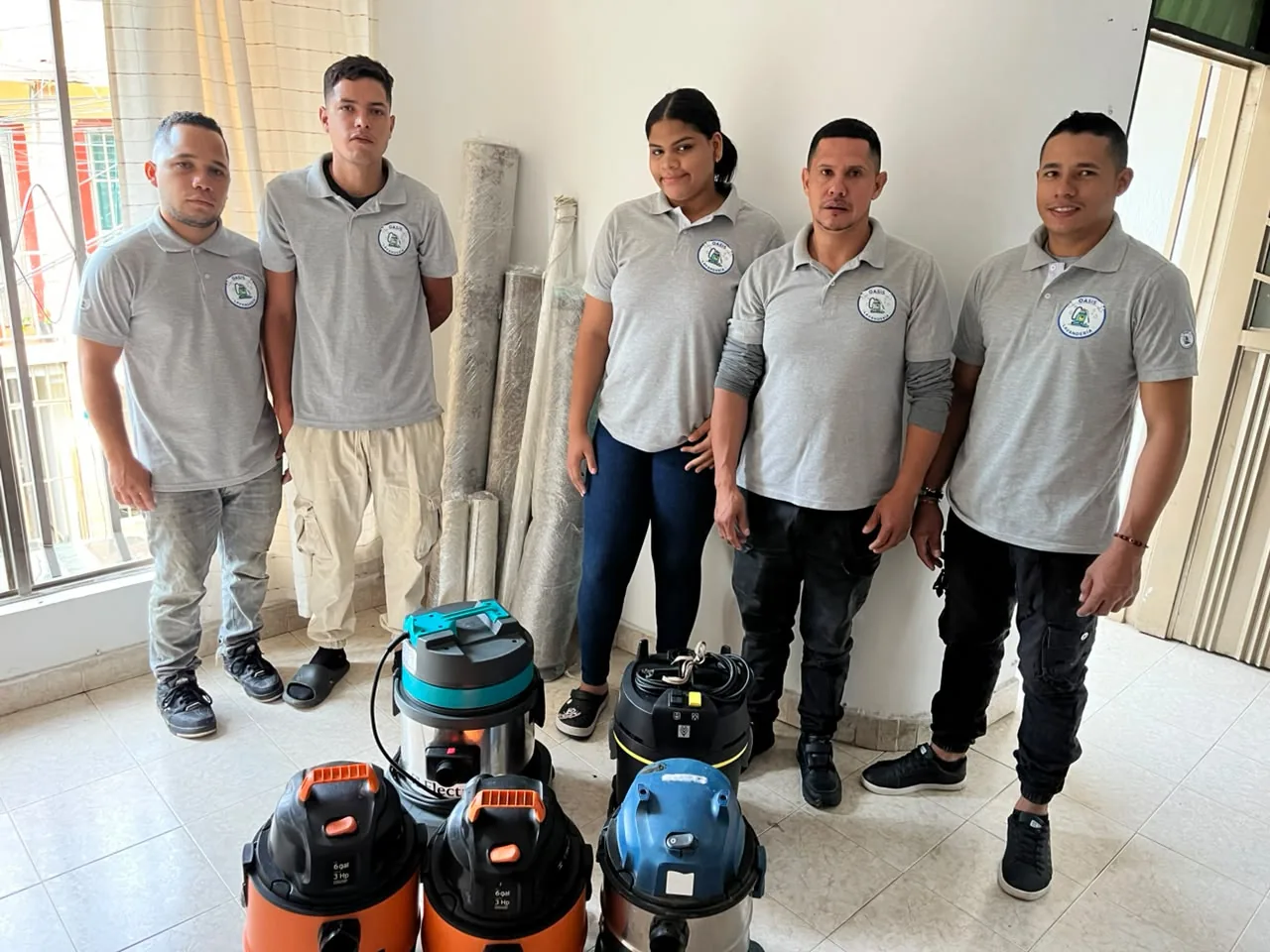 Equipo de Oasis Lavandería en Cali uniformado junto a sus cinco máquinas de extracción profesional
